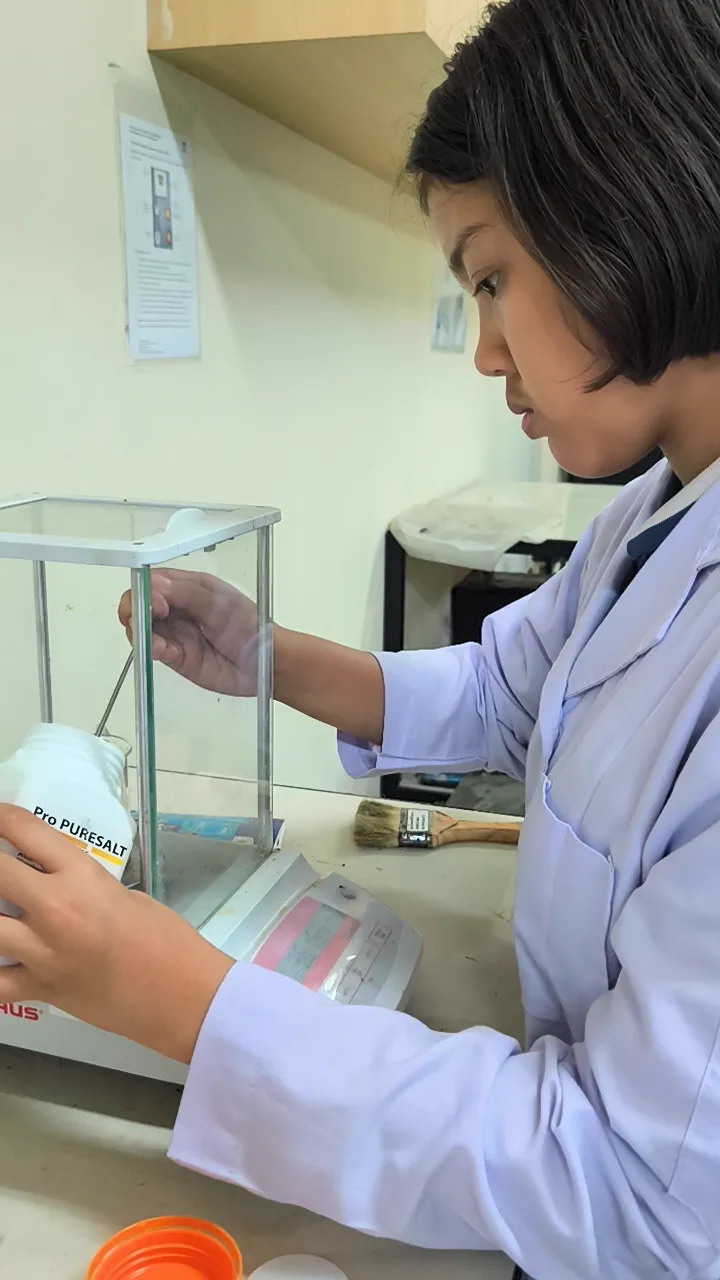Peneliti muda melakukan penimbangan analitik presisi di laboratorium